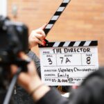 Close-up of film clapperboard in action with camera filming a take on set.